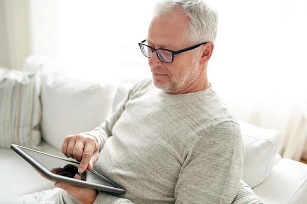 Senior man using a tablet with assistive listening technology at home